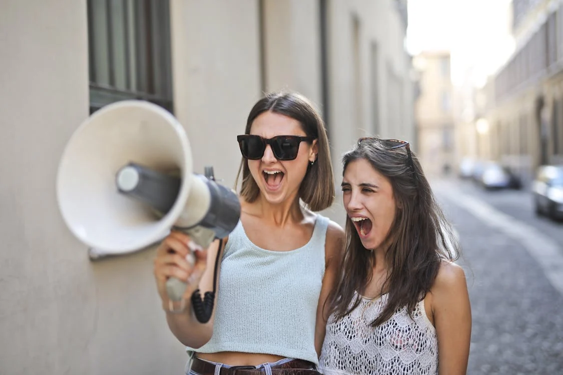 Two women smiling and yelling with a megaphone